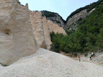 Low angle view of people on rock against sky
