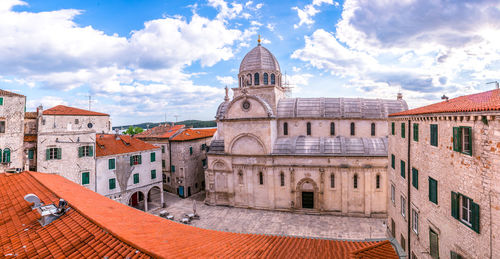 Buildings in town against cloudy sky