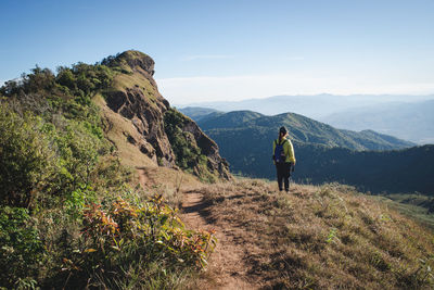 Rear view of man standing on mountain against sky