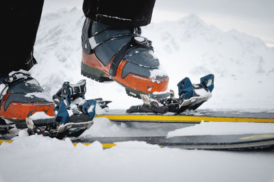 Close-up of the legs of an athlete-skier in ski boots against the backdrop of snow-capped mountains