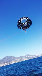 Low angle view of person parasailing over sea against clear sky