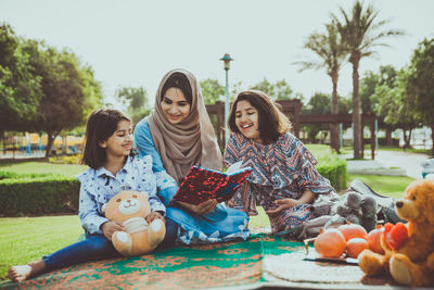 Rear view of mother and girl sitting on floor