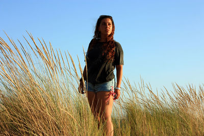 Caucasian girl posing among the shrubs in sea dunes at the warm and bright time of sunset in tuscany