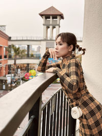 Side view of woman sitting on railing