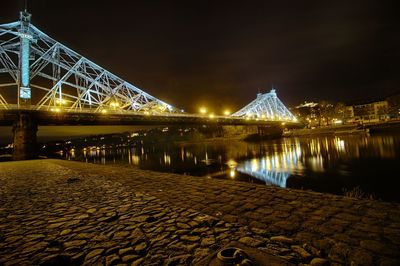 Illuminated bridge over river at night