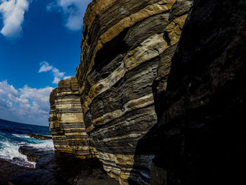 Rock formation by sea against sky