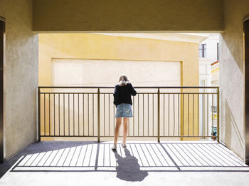 Rear view of woman standing against railing