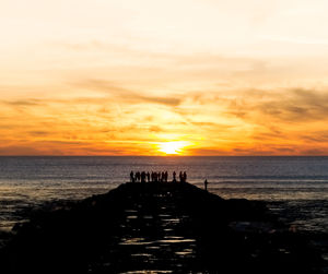 Silhouette pier over sea against sky during sunset