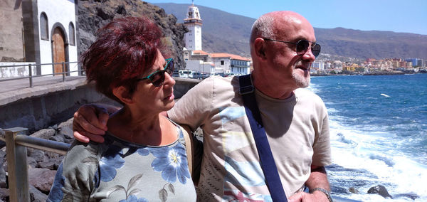 Senior couple standing against sea