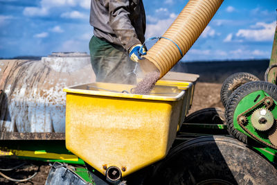 Low section of person working on barbecue grill against sky