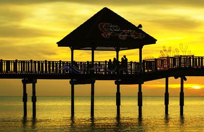 Silhouette pier over sea against sky during sunset