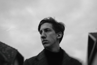 Portrait of young man looking away against sky