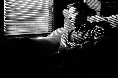 Man sitting on chair by window at home