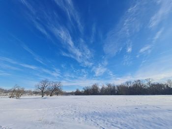 Snow covered field against blue sky