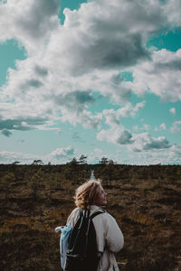 Rear view of woman standing on field against sky