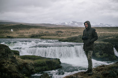 Man standing in waterfall against sky