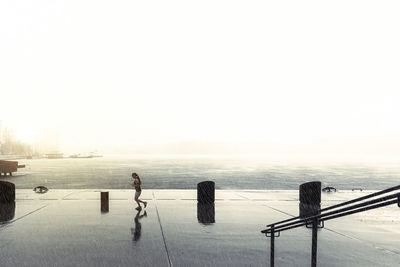 People standing on railing by sea against clear sky