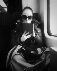 Young woman using digital tablet while sitting in train