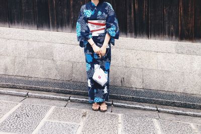 Low section of woman standing on footpath