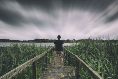 Rear view of man standing on field against sky