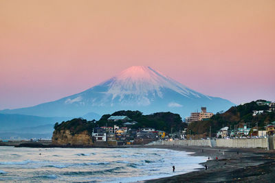 Scenic view of sea and snowcapped mountain against sky during sunrise