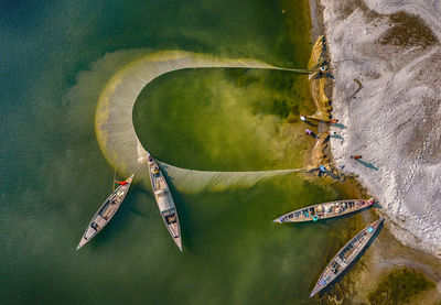 People pulling fishing net at coastline at beach