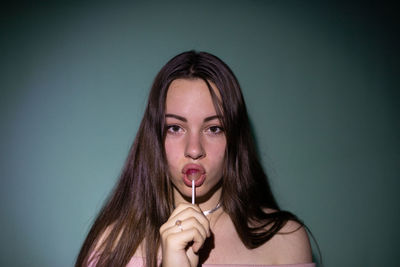 Portrait of beautiful young woman licking lollipop