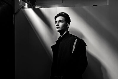 Portrait of young man standing against wall