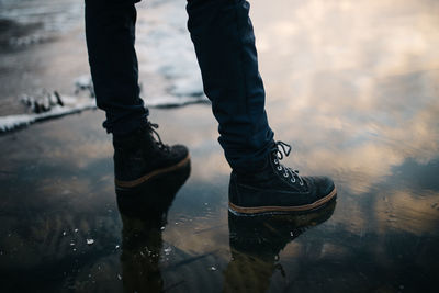 Low section of man standing in a frozen lake