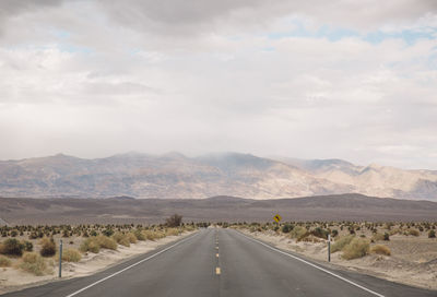 Road by mountains against sky