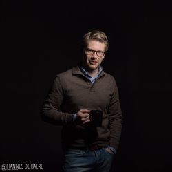 Portrait of young man standing against black background