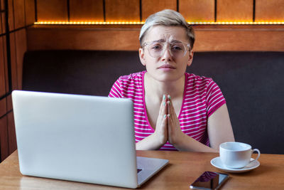 Portrait of woman using mobile phone while sitting on table