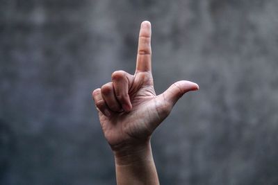 Cropped image of hand pointing against wall