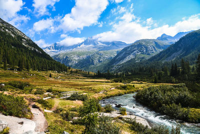 Scenic view of stream by mountains against sky