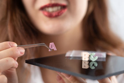 Close-up of woman holding alphabet with hand tool