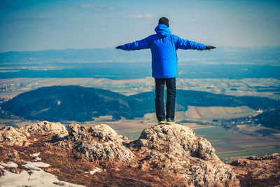 Rear view of man looking at mountains against sky