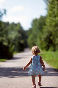 Rear view of woman walking on road