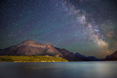 Scenic view of lake and mountains against sky at night