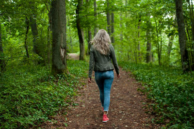 Woman walking on footpath in forest