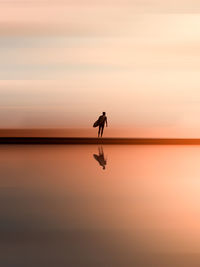 Silhouette man on beach against sky during sunset