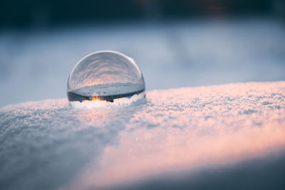 Glass transparent ball in the snow in winter, sun rays reflection. severe frost, cold