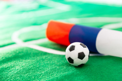 Close-up of small soccer ball with flag on green textile