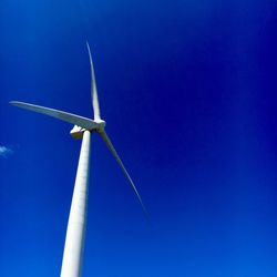 Low angle view of windmill against blue sky