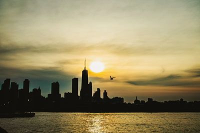 Silhouette buildings in city against sky during sunset