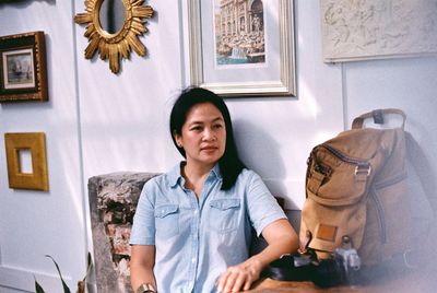 Mature woman looking away while sitting against wall