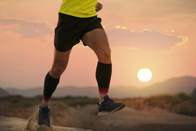 Low section of man running against sky during sunset