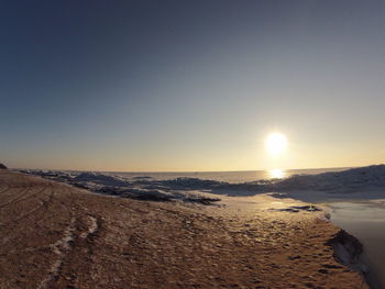 Scenic view of beach against clear sky at sunset