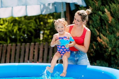 Mom and daughter have fun in the pool in the garden, dipping into the warm water