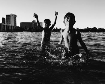 Children playing in sea against clear sky