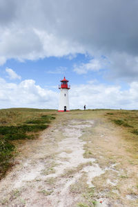 Lighthouse on field against sky